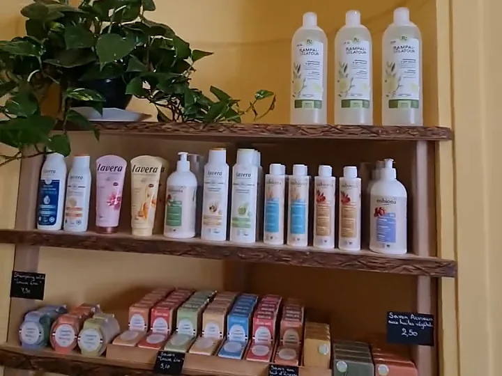 Étagère en bois avec des shampoings, des gels douche et des savons solides.